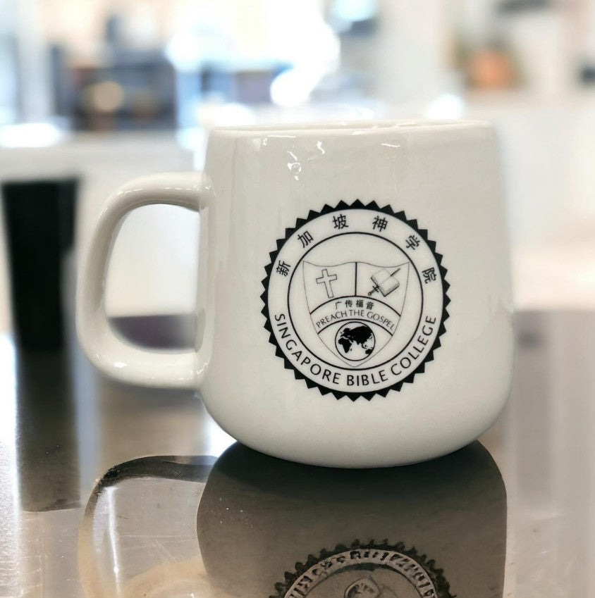 Multiple customised coffee mugs in various designs with corporate logos on modern office setting