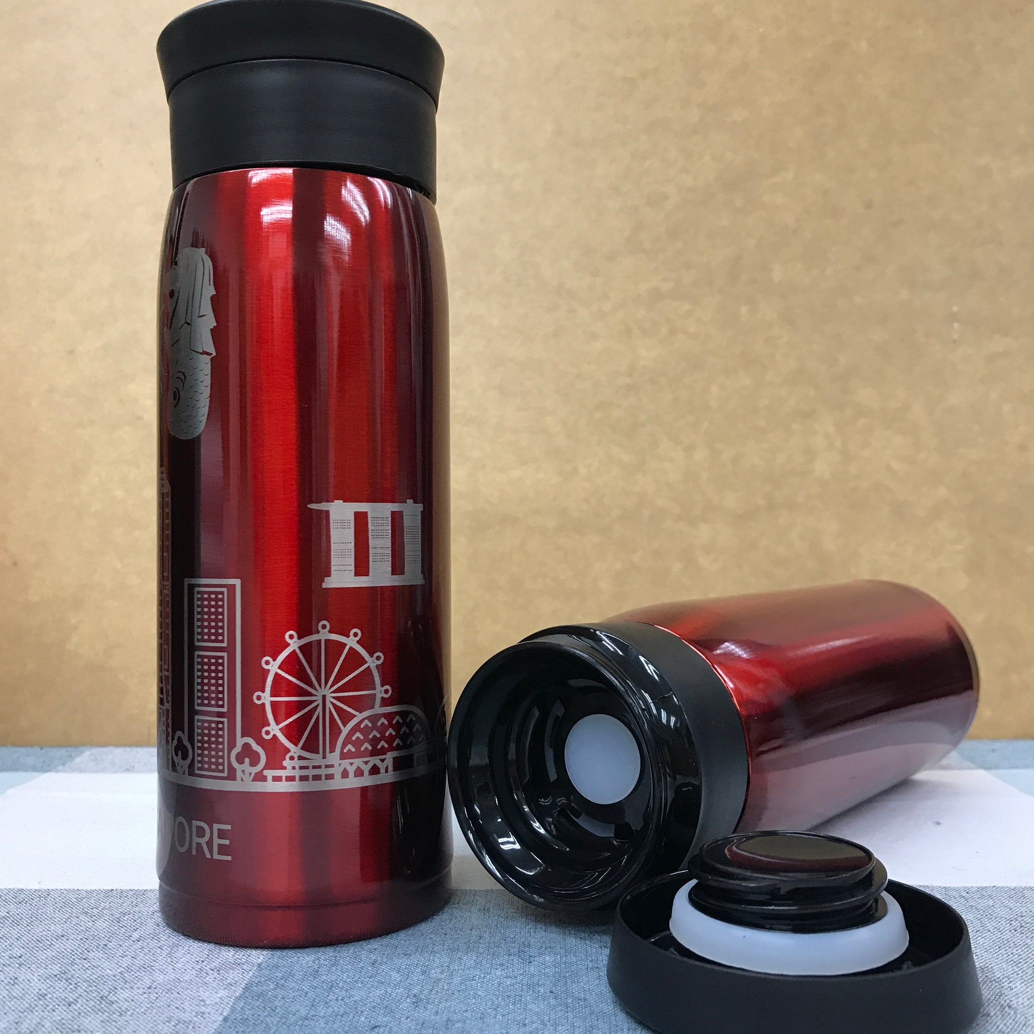 Multiple custom thermos flasks in various colors with corporate logos on office desk