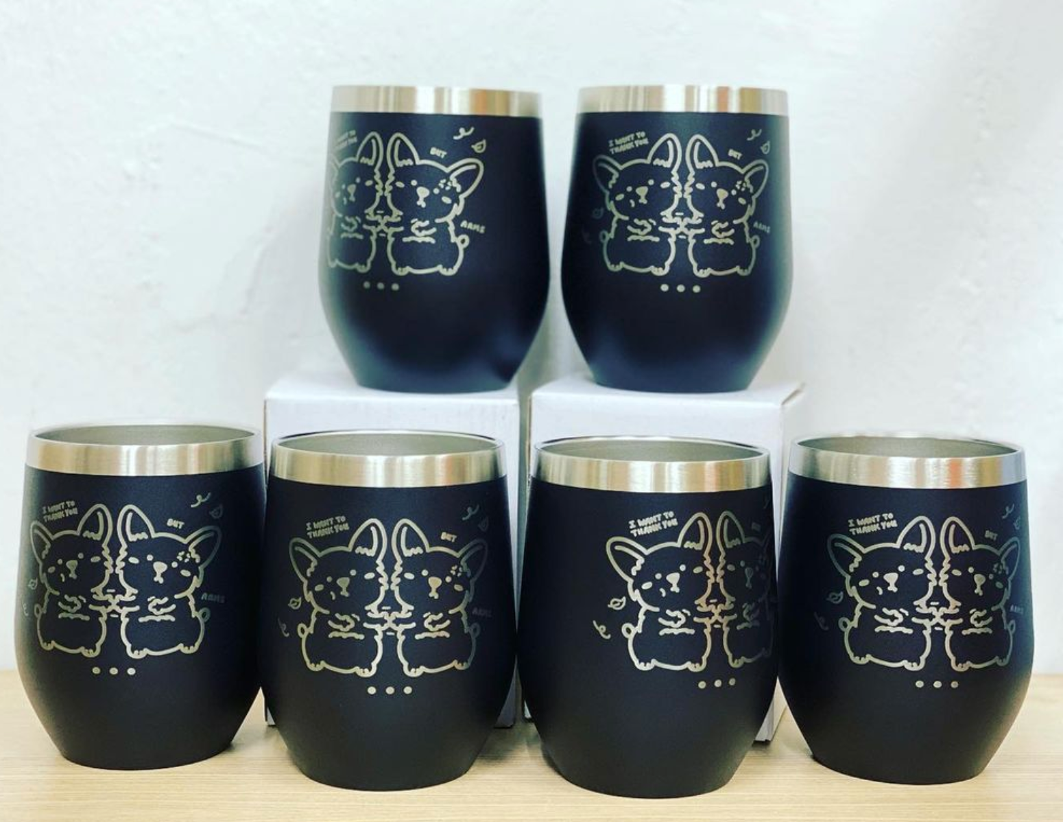 Multiple custom tumblers in various colors with corporate logos on marble conference table