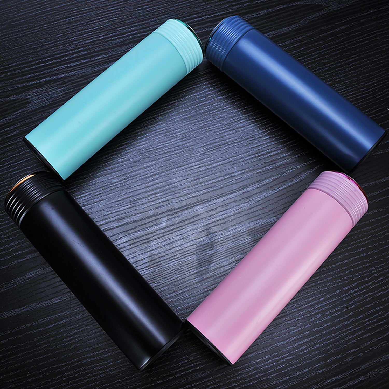 Multiple custom thermos flasks in various colors with corporate logos on marble conference table